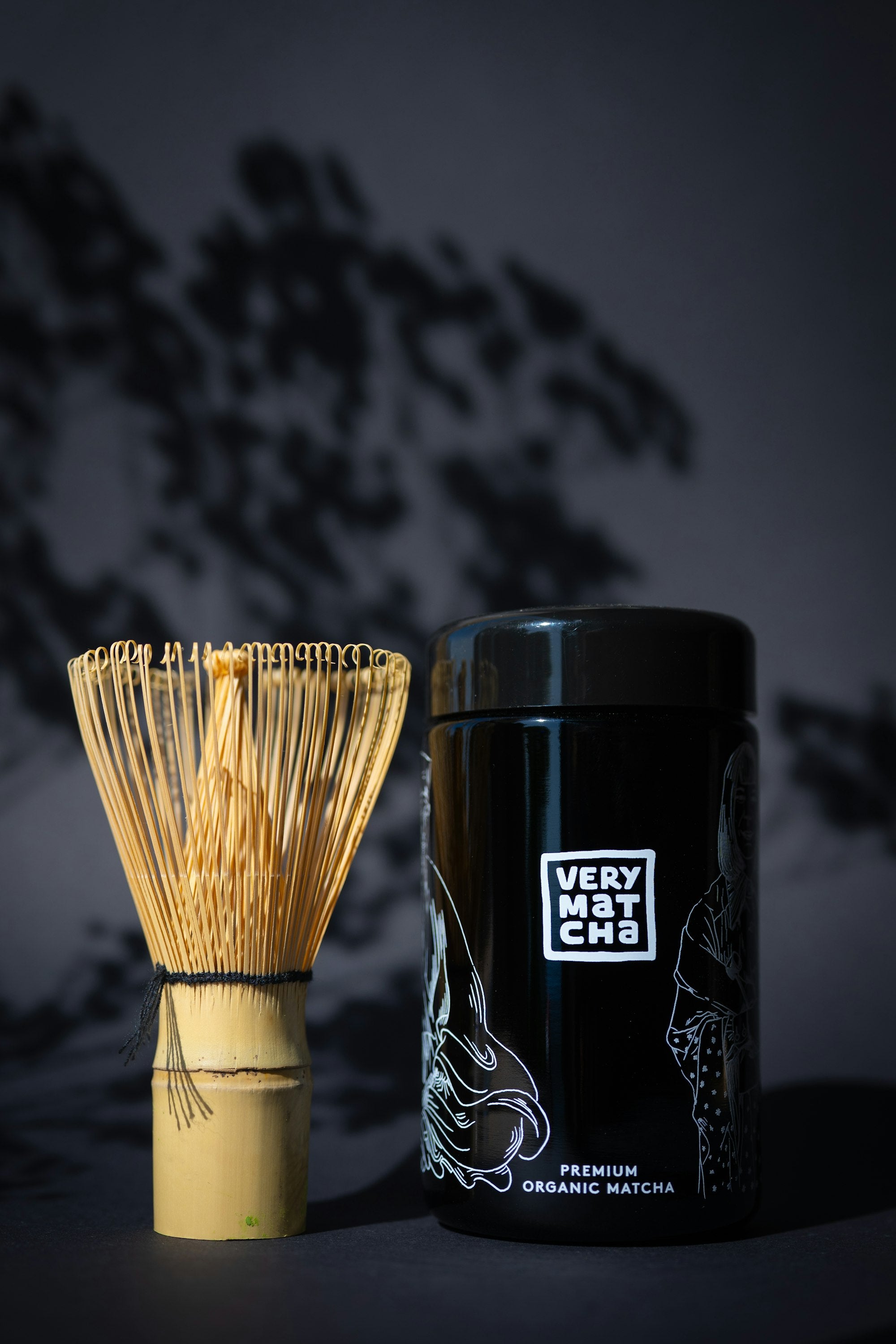 Chasen de bambu e recipiente de matcha sobre fundo escuro
